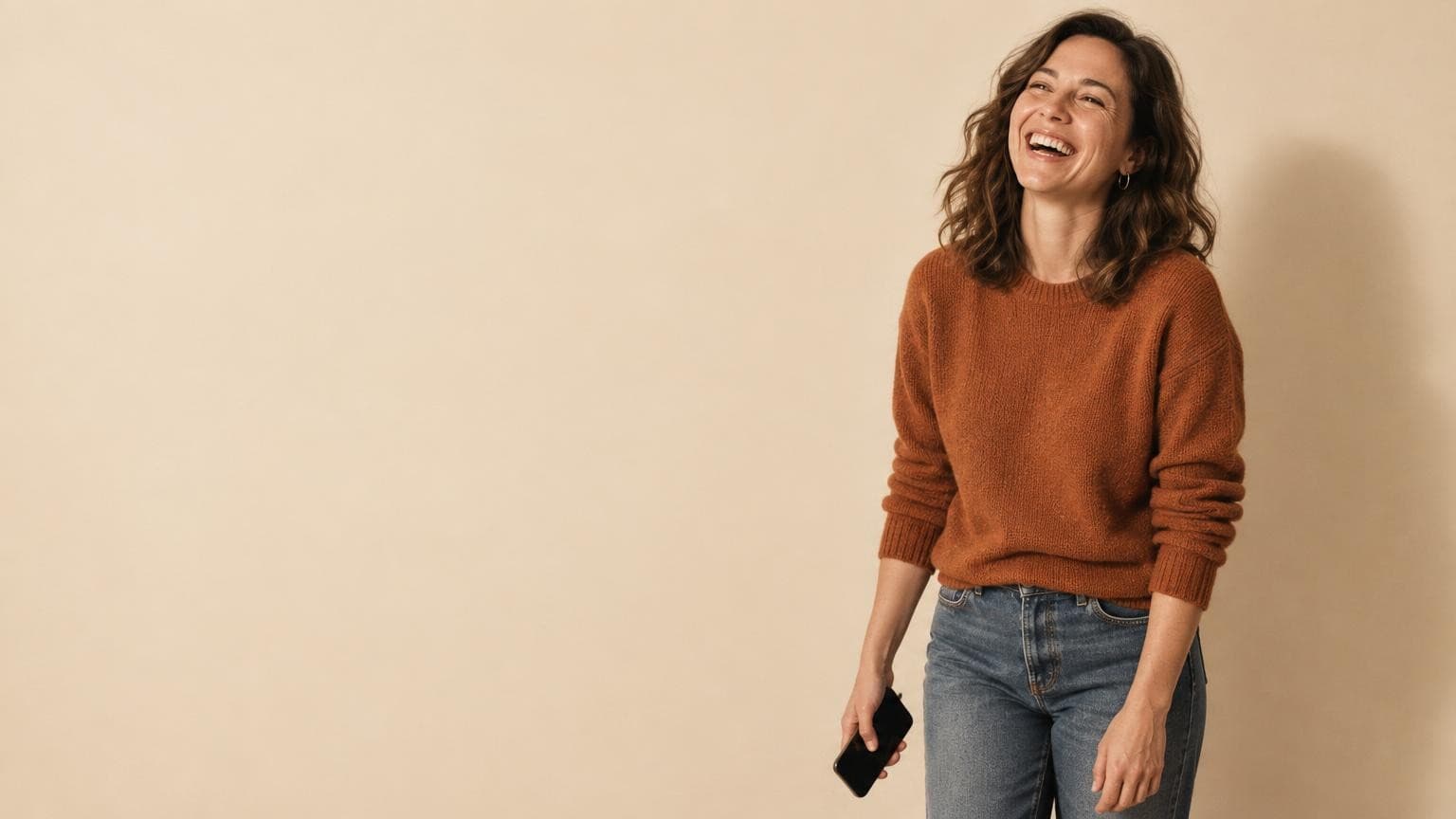 A woman laughing with her phone in her hand, her social media already handled